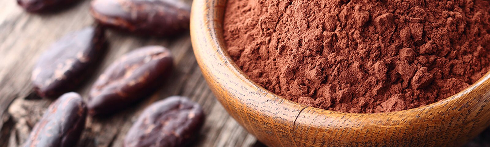 Cacao powder in a bowl next to nibs on a table