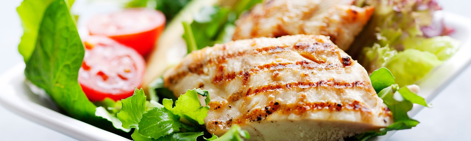 Cooked chicken breast on a bed of greens Cooked chicken breast on a bed of greens