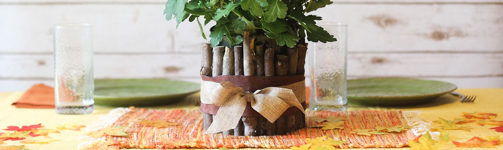 Finished DIY wood vase with a brown ribbon around the base and a potted plant inside on a dinner table