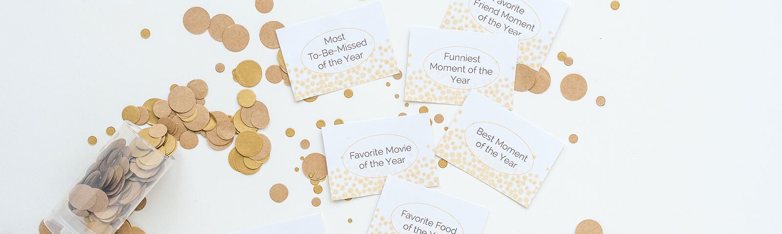 White cards with New Year's prompts printed on them surrounded by large gold confetti